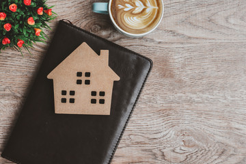 Top view of business desk at home office with blank notepad,model house,cup coffee Copy space. Work from home and stay at home concept