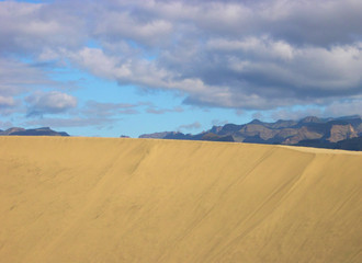 Beautiful view of the mountains behind a dune in Maspalomas beach. South of Gran Canaria Island. Spain.