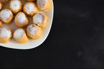 buns lie on a white square plate on a black background in the left corner of the table.