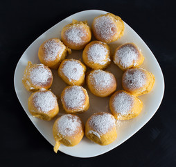 Many buns lie on a white square plate on a black background.
