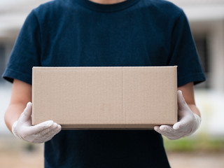 Delivery Man Wearing Protective Face Mask Holding Package in Front of House