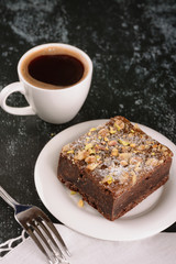 Brownie cake and freshly brewed black coffee for breakfast or dessert on a dark background