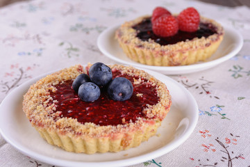 A cake in the shape of a basket of shortcrust pastry with jam filling and decorated with blueberries and raspberries on top