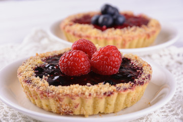 A cake in the shape of a basket of shortcrust pastry with jam filling and decorated with blueberries and raspberries on top