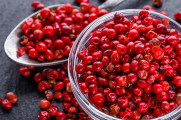pink peppercorns on a dark stone background