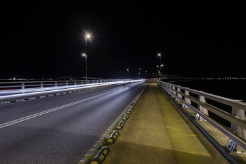 Fototapeta na wymiar light from car lights in the night on a bridge
