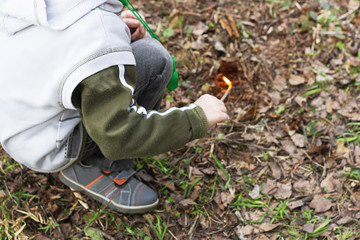 A child plays with fire in the forest.