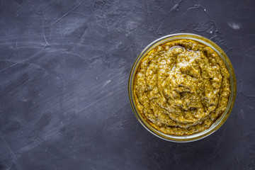 Delicious traditional italian pesto sauce on dark stone background