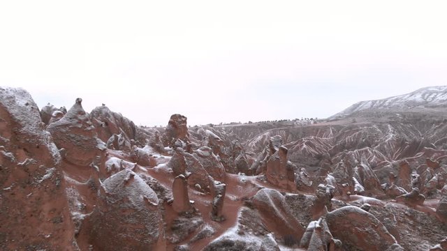 Fairy chimneys and cave houses surrounded by rock formations at Imaginary Valley in Cappadocia, Turkey. Tufa formations covered with snow in Devrent Valley in Cappadocia