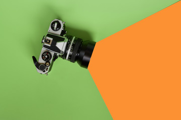 Concept image. Still life of vintage retro photo camera. Virtual viewing angle. Green and orange background.