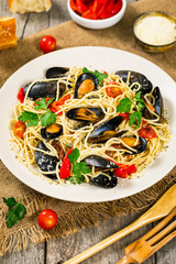 Seafood Pasta Spaghetti with Mussels and Tomatoes on Wooden Background. Italian Cuisine. Selective focus.