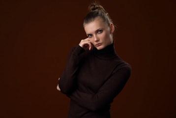 Beautiful girl in a maroon turtleneck on a brown background