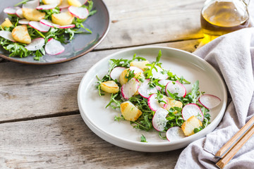 fresh salad with arugula, radish, baked potatoes and aromatic herbs with olive oil