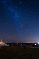 milky way sky with a silhouette man flashing a lantern to the sky