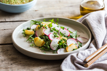fresh salad with arugula, radish, baked potatoes and aromatic herbs with olive oil