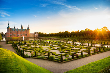 Sunset view of Frederiksbork palace castle, where is a famous landmark for travel and visit museum, with beautiful garden and fountain water at sunset time in Hillerod, near Copenhagen, Denmark, Europ