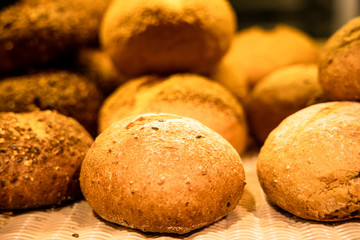 Pile of rustic bread in a bakery. Sourdough bread. Multi-grain bread. Whole wheat bread. Background of rustic bread.
