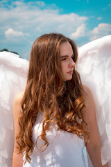 A large portrait of a beautiful girl with long hair in the image of an angel with white wings.