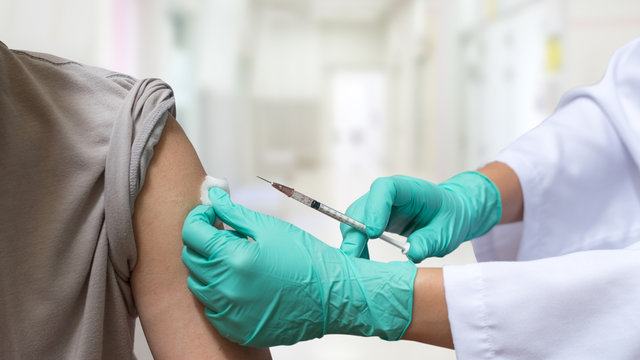 COVID-19, coronavirus concept. World immunization week of man having vaccination for influenza or flu shot with syringe by nurse or doctor medical officer in hospital. - Powered by Adobe