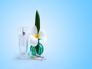 Spa white plumeria flowers in green vase with clear glass perfume bottle isolated on blue background with copy space for text design.