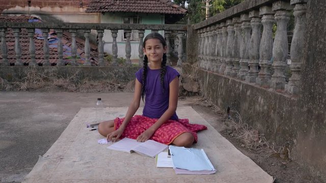 India, Goa. February 27, 2019
Indian girl doing homework on the roof.