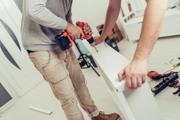 Two men are renovating and decorating the new apartment.