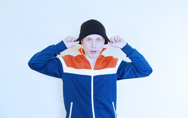 Young man in a sports sweater and hat on a light background