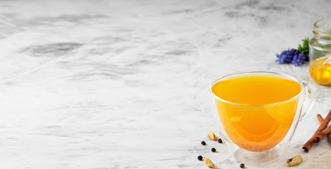 Turmeric and spices - herbal tea on a gray background. Jar of honey and spices are the ingredients for making tea. Traditional drink to support immunity against flu and the common cold. Close up