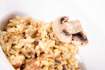 Risotto with button mushroom and bacon decorated with mushroom on a plate on a white background