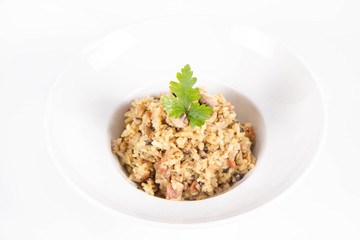 Risotto with button mushroom and bacon decorated with parsley on a plate on a white background