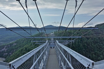 Skybridge is one of the longest suspension footbridges in the world. A bridge of metal and concrete over a deep gorge and river. Lattice floor and railings, magnificent views of the Caucasus Mountains