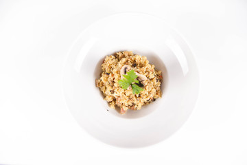 Risotto with button mushroom and bacon decorated with parsley on a plate on a white background