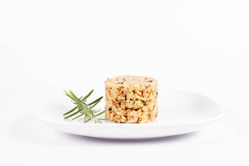 Risotto with button mushroom and bacon decorated with a rosemary twig on a plate on a white background