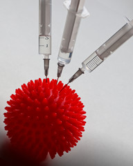 Syringe and red Coronavirus symbol. Injection of a cure for the virus COVID-19. Medical concept of...