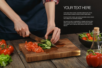 Woman cooking fresh healthy salad. Female hands cutting vegetables on board on wooden table with sample text.