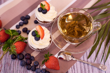 Cupcakes with strawberries and blueberries. Cupcakes with a cup of tea. Selective focus.
