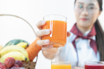 A cute girl makes vegetable juice, with carrot apple orange cranberry beetroot and mango in chef suit.