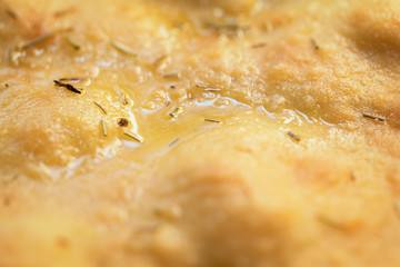 Close up of a greasy surface of pizza with rosemary.
