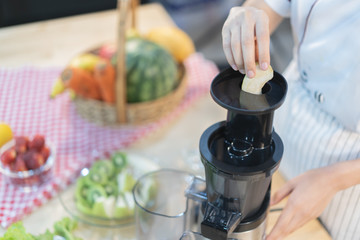 A cute girl makes vegetable juice, with carrot apple orange cranberry beetroot and mango in chef suit.