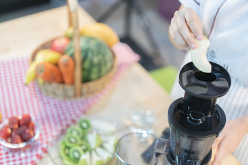 A cute girl makes vegetable juice, with carrot apple orange cranberry beetroot and mango in chef suit.