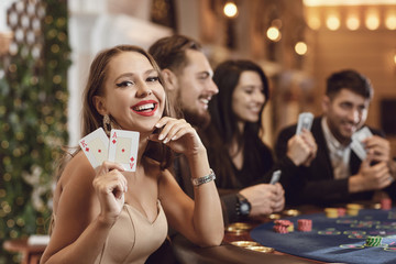 Girl with cards in her hands smiles at winning poker in a casino.