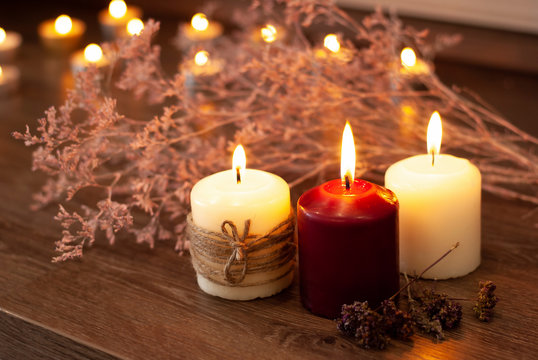 Aromatherapy flame closeup picture. Beautyful burning light wine red candles with wooden background and dry flowers