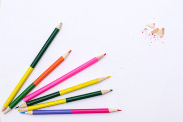 colored pencils are scattered along with  pencil shavings on a white background