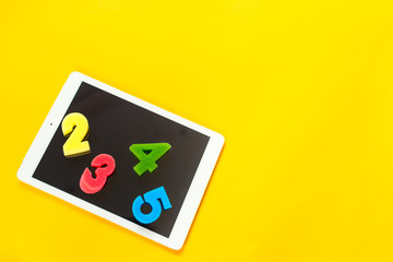 school paint supplies and tablet on a yellow isolated background, theme back to school