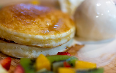 pancake with vanilla ice-cream ,whipped cream, mixed fruits and honey. Pancakes in syrup and ice cream. Closeup of pancakes with fresh fruits, ice cream and whipped cream.