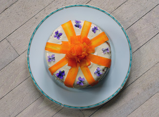 Vegan carrot cake with candied carrot ribbons and fresh violet flowers