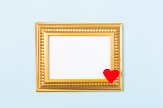 Golden frame empty blank picture with red heart on light blue background . Copy space free space for text. Holiday card concept. Mock up. Greeting. Mother's Day. St Valentine's Day. Love .