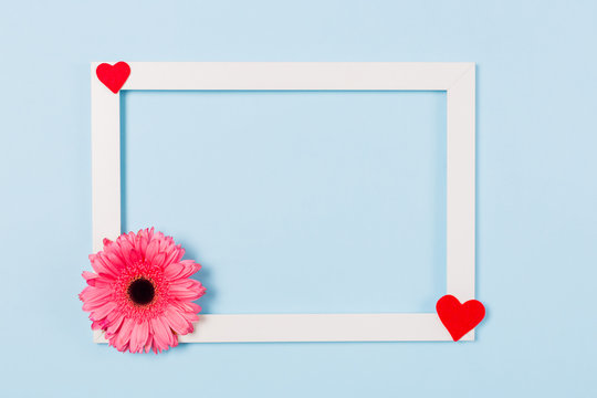 White frame empty blank picture with pink flower in corner on light blue background . Copy space free space for text. Holiday card concept. Mock up. Greeting. Mother's Day. St Valentine's Day. Love . 
