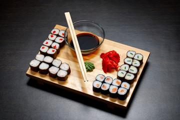 Tasty and delicious hot and cold sushi rolls on the table. Different sushi - rolls with sauce on the board of Japanese cuisine.