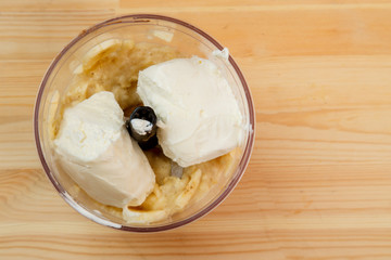 Sliced bananas and balls of ice cream in a blender bowl for chopping.